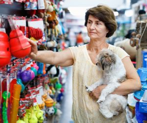Lady hold her dog while picking the safest dog chews and toys